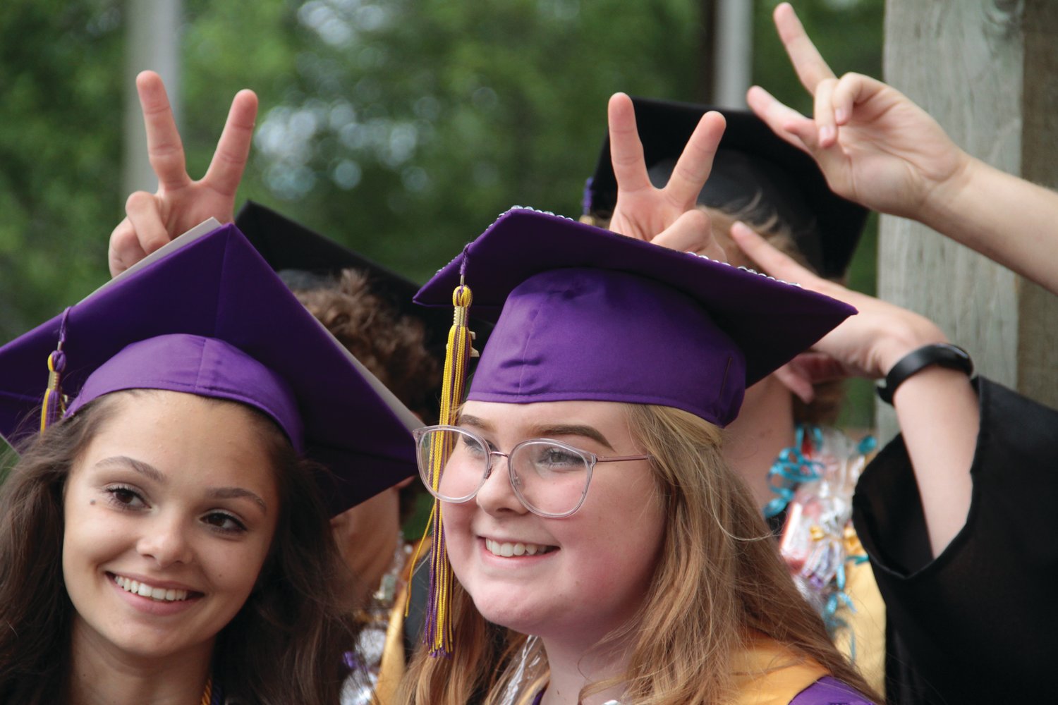 Shelby Love and Natalie Coffee get rabbit-eared by their classmates while posing for a photo before the start of the graduation ceremony Saturday.
